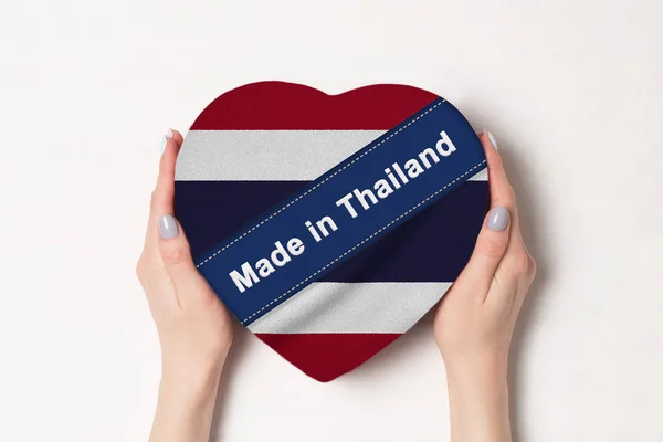 Inschrift in thailand die thailändische Flagge. Frauenhände mit einer herzförmigen Schachtel. weißer Hintergrund. — Stockfoto