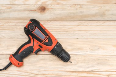 Açık kahverengi ahşap bir masa üzerinde yatan elektrikli matkap tornavida. Ahşap. Doğrudan yukarıda, kopyalama alanı.