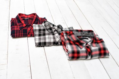 Beyaz ahşap arka plan üzerinde üç ekose gömlek. Giyim konsepti. Üstte görüntü