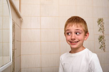 Gülümseyen scholboy banyo aynasında görünüyor. Sabah