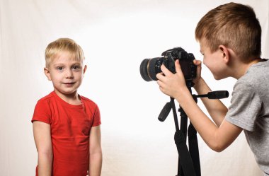 Küçük sarışın çocuk röportaj vermeye hazır, çocuk video kameraya alır. Genç video blogcusu. Beyaz arka plan