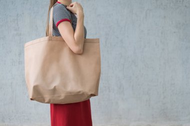 Genç bir kadının omzunda büyük bir eko alışveriş çantası. Tasarım alanı