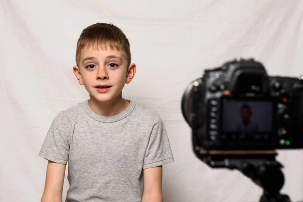 El colegial dice algo en una videocámara. Joven video blogger. Fondo blanco —  Fotos de Stock