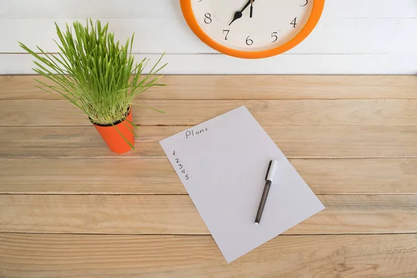 Foglio bianco di carta con un piano scritto e penna, pianta d'appartamento verde. Pianificazione aziendale — Foto Stock