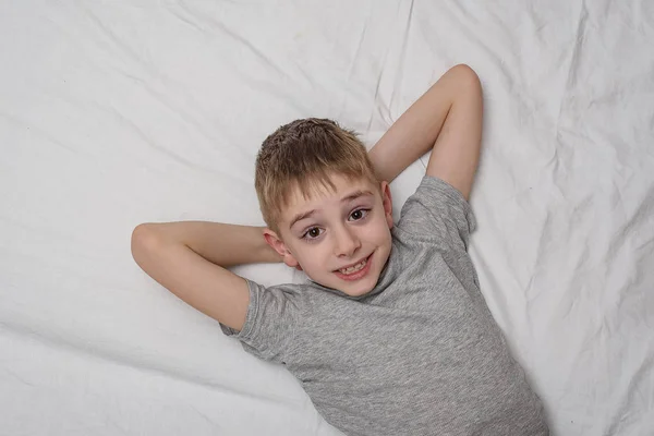 Uśmiechnięty chłopak leżący na łóżku. Widok z góry, Kopiuj spację. — Zdjęcie stockowe