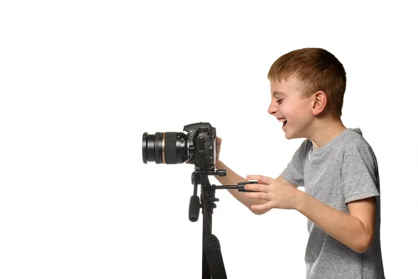 Lo scolaretto ridente gira un video sulla fotocamera DSLR. Vista laterale. Fondo bianco, isolare — Foto Stock