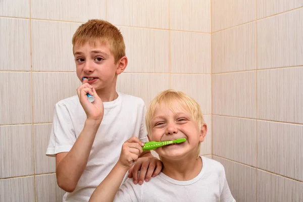 Dois rapazes escovam bem os dentes na casa de banho. Limpeza matinal — Fotografia de Stock