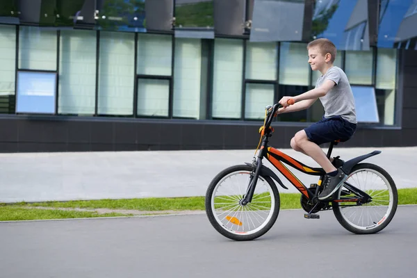 Schoolboy lovagol egy kerékpárt. Nyári szünidő. Városi háttér — Stock Fotó