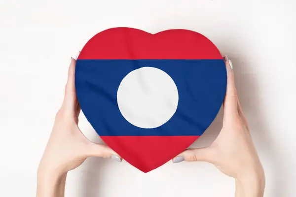 Flagge von Laos auf einer herzförmigen Schachtel in weiblichen Händen. weißer Hintergrund — Stockfoto
