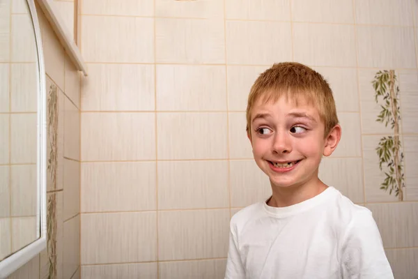 Smiling scholboy looks in the bathroom mirror. Morning — Stock Photo, Image
