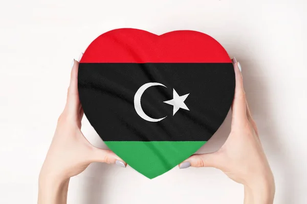 Bandera de Libia en una caja en forma de corazón en manos femeninas. Fondo blanco — Foto de Stock