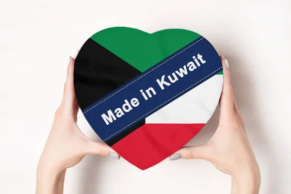Felirat Made Kuvaitban, a lobogó Kuvait. Egy szív alakú dobozt tartó női kéz. Fehér háttér. — Stock Fotó