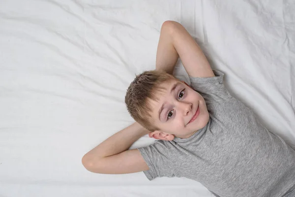 Uśmiechnięty chłopak leżący na łóżku. Widok z góry, Kopiuj spację. — Zdjęcie stockowe