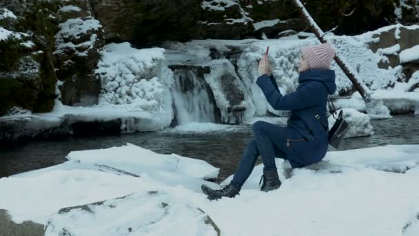 Young Woman Sits Shore Small Waterfall Shoots Video Smartphone Winter — Stock Video