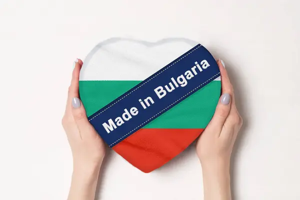 Inscripción Hecho en Bulgaria la bandera de Bulgaria. Manos femeninas sosteniendo una caja en forma de corazón. Fondo blanco . —  Fotos de Stock