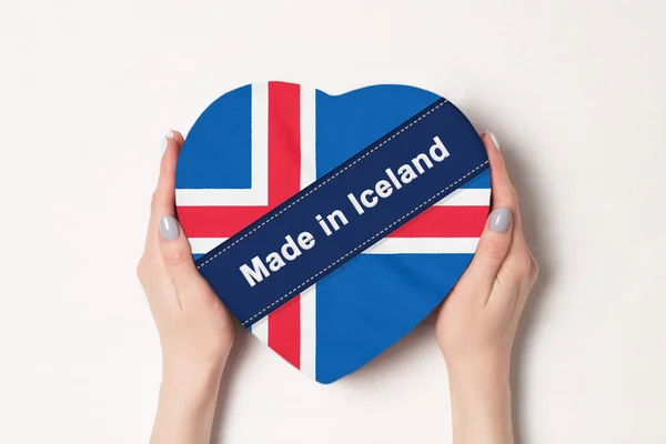 Inskripsi yang dibuat di Islandia bendera Islandia. Tangan wanita memegang kotak berbentuk hati. Latar belakang putih . — Stok Foto