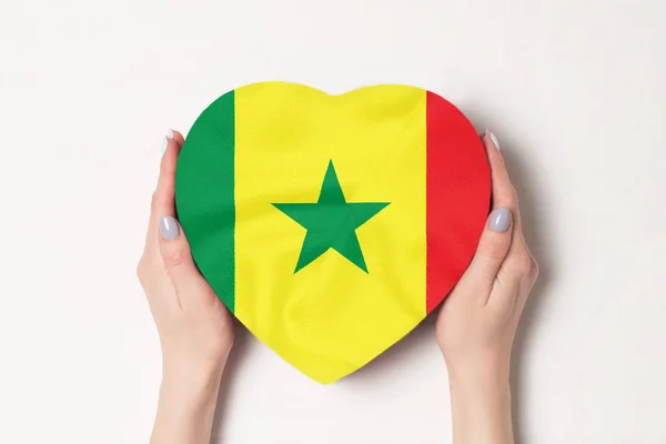 Σημαία της Σενεγάλη σε ένα κουτί σε σχήμα καρδιάς σε γυναικεία χέρια. Λευκό φόντο — Φωτογραφία Αρχείου