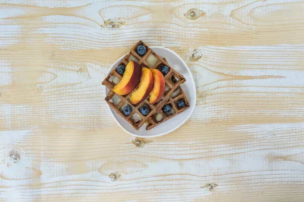 Schokolade belgische Waffeln mit Früchten und Beeren auf weißem Holzgrund. leckeres Frühstück. Ansicht von oben — Stockfoto