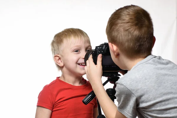 Os rapazes estão a fotografar-se uns aos outros com uma câmara SLR. Jovem blogueiro. Fundo branco — Fotografia de Stock