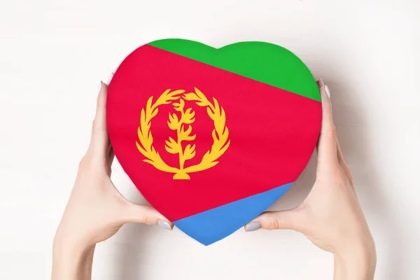 Σημαία της Ερυθραίας σε ένα κουτί σε σχήμα καρδιάς σε γυναικεία χέρια. Λευκό φόντο — Φωτογραφία Αρχείου