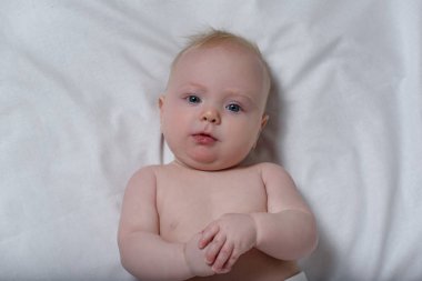 Beyaz bir çarşaf üzerinde sevimli bir sarışın bebek portresi. Üstte görüntü