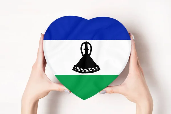 Bandera de Lesotho en una caja en forma de corazón en manos femeninas. Fondo blanco — Foto de Stock