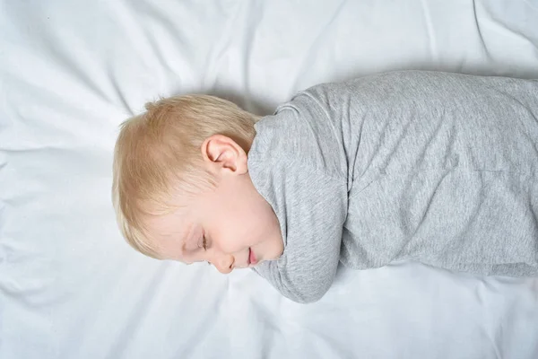 Mignon garçon blond dormant avec sa main sous la tête. Fond blanc — Photo