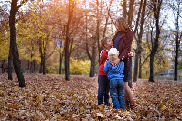 Two boys hug their pregnant mom. Family concept. Autumn park on the background — Stock Photo, Image