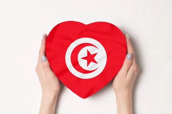 Bandera de Túnez en una caja en forma de corazón en manos femeninas. Fondo blanco — Foto de Stock