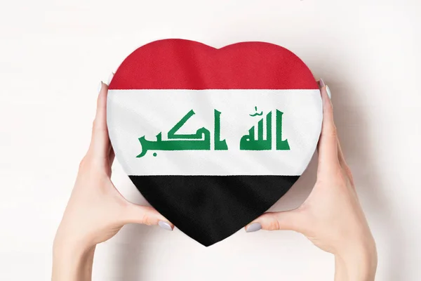 Flagge des Irak auf einer herzförmigen Schachtel in weiblichen Händen. weißer Hintergrund — Stockfoto