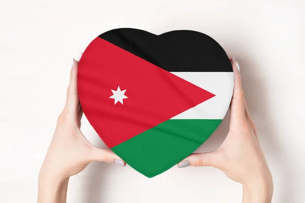 Bandera de Jordania en una caja en forma de corazón en manos femeninas. Fondo blanco — Foto de Stock