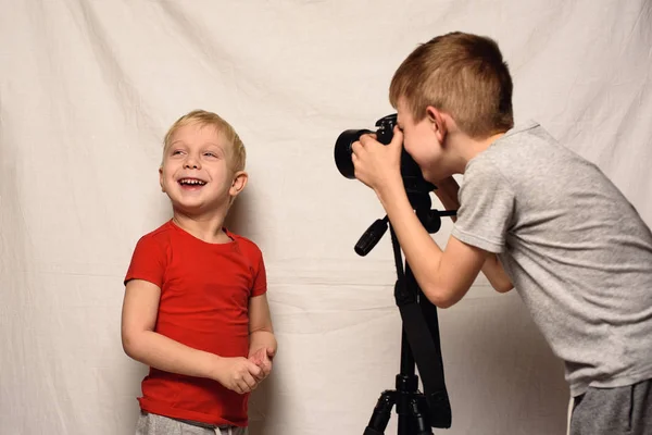 I ragazzi si fotografano a vicenda con una fotocamera reflex. Studio casalingo. Giovane blogger. Fondo bianco — Foto Stock