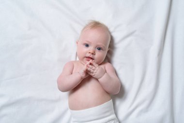 Beyaz bir çarşaf üzerinde sevimli bir sarışın bebek portresi. Üstte görüntü