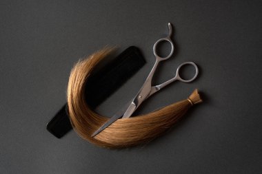 Kesilmiş bukle sarışın örgü, tarak ve makas. Siyah arka plan. Close