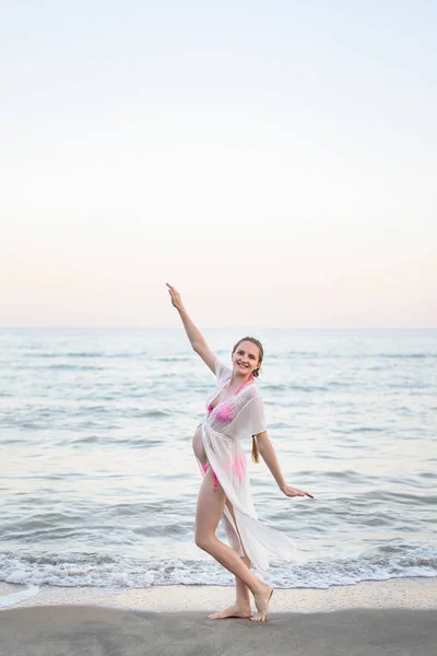 Молода вагітна жінка танцює на березі моря. Насолоджуйтесь миттю . — стокове фото