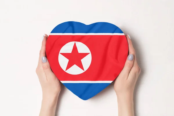 Bandera de Corea del Norte en una caja en forma de corazón en manos femeninas. Fondo blanco —  Fotos de Stock