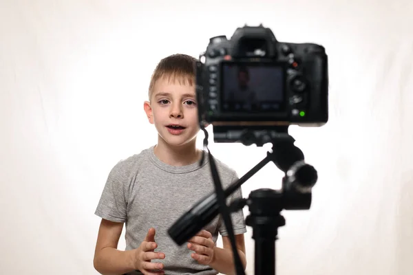School jongen zegt iets op een camcorder. Jonge videoblogger. Witte achtergrond — Stockfoto