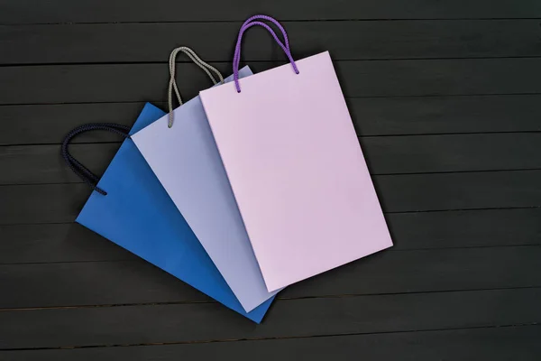 Papír multi-barevné nákupní tašky na černém dřevěném pozadí. Horní pohled. — Stock fotografie