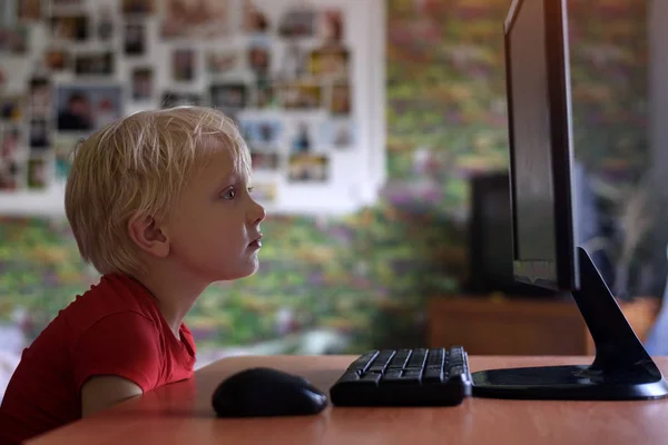 Niño rubio cansado se sienta con la nariz enterrada en un monitor PC. Internet y preescolar — Foto de Stock