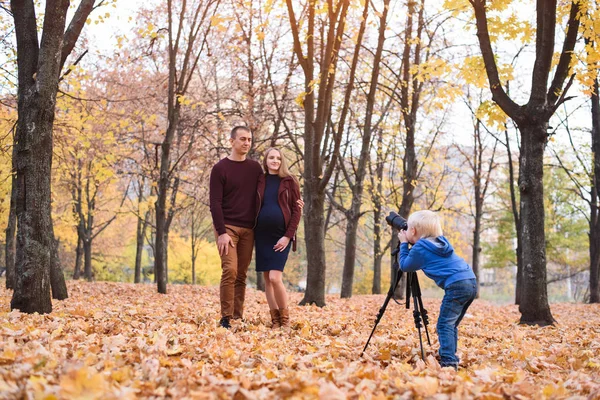 Um rapaz louro com uma grande câmara SLR num tripé. Fotografias de um casal, gravidez. Sessão de fotografia familiar — Fotografia de Stock