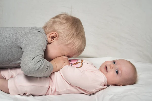 El hermano mayor rubio juega con su hermana pequeña. Interacción infantil —  Fotos de Stock
