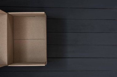 Siyah ahşap arka planda boş karton kutu. Teslimat konsepti. Üst görünüm