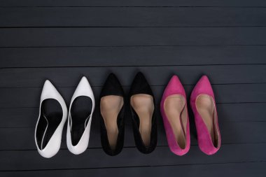 Üç çift farklı yüksek topuklu ayakkabı. Siyah tahta arkaplan.