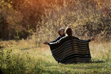 Anne koşan oğluyla kolları açık tanışır. Arkadan bak. Sonbahar ormanı