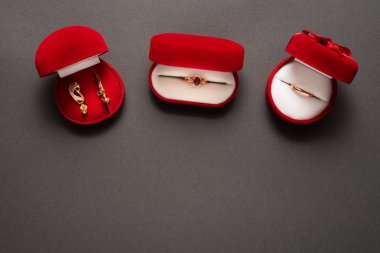 Siyah arka planda mücevherleri olan üç kırmızı mücevher kutusu. Üst görünüm