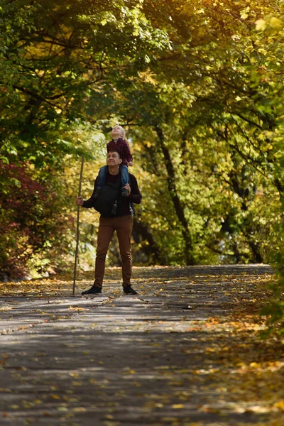 Pai com filho em seus ombros andando no parque de outono . — Fotografia de Stock