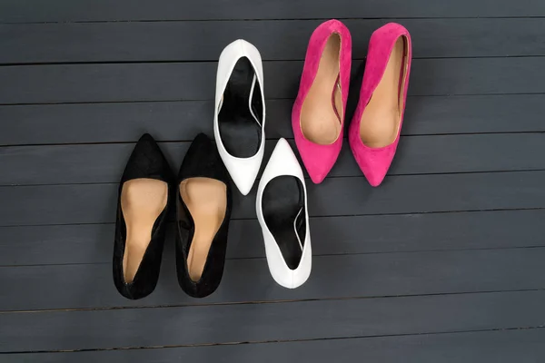 Sapatos de salto alto feminino em cores diferentes. Fundo de madeira preta. Conceito de moda — Fotografia de Stock
