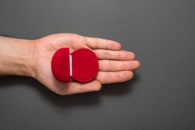 Erkek avucundaki boş kırmızı mücevher kutusu. Hediye. Siyah arka plan. Üst görünüm