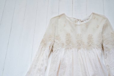 Beyaz arka planda nakışlı bej bir bluz. Kıyafet konsepti