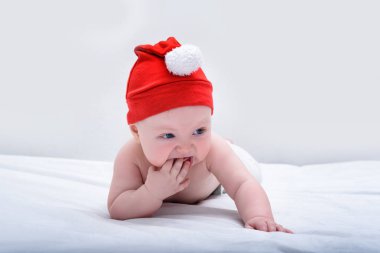 Noel Baba şapkalı şirin bir bebek göbeğinde çıplak yatıyor. Beyaz arkaplan